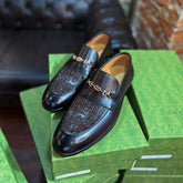 Black loafers on a green Gucci box with a blurred background